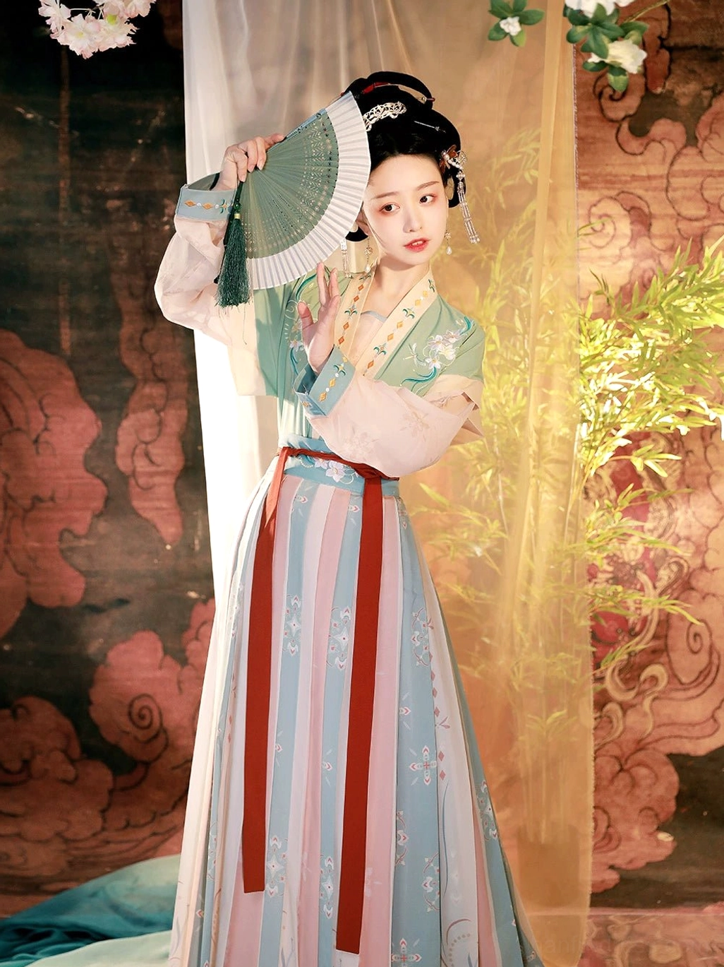 Full-length green Tang Dynasty Hanfu costume with embroidered half sleeve top, striped pleated skirt, red waist sash, and folding fan