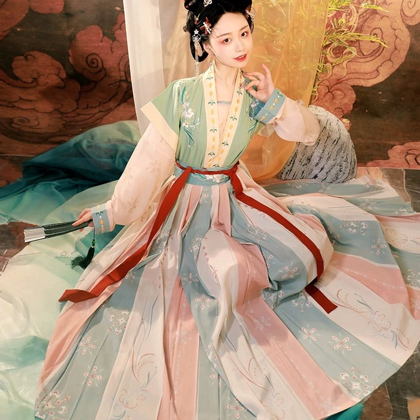 Green Tang Dynasty Hanfu beizi qiyao ruqun sitting view showing the flowing pastel striped pleated skirt, red sash, and layered vest