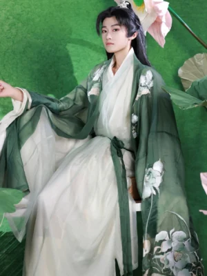 Three-quarter view of a male model in a green and white xianxia Hanfu outfit with embroidered lotus sleeves, cross-collar inner robes, matching waist sash, and long flowing coat