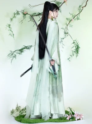Rear three-quarter view of green ink-wash Xianxia Hanfu robe with flowing sheer overlay, wide sleeves, and long traditional sword prop
