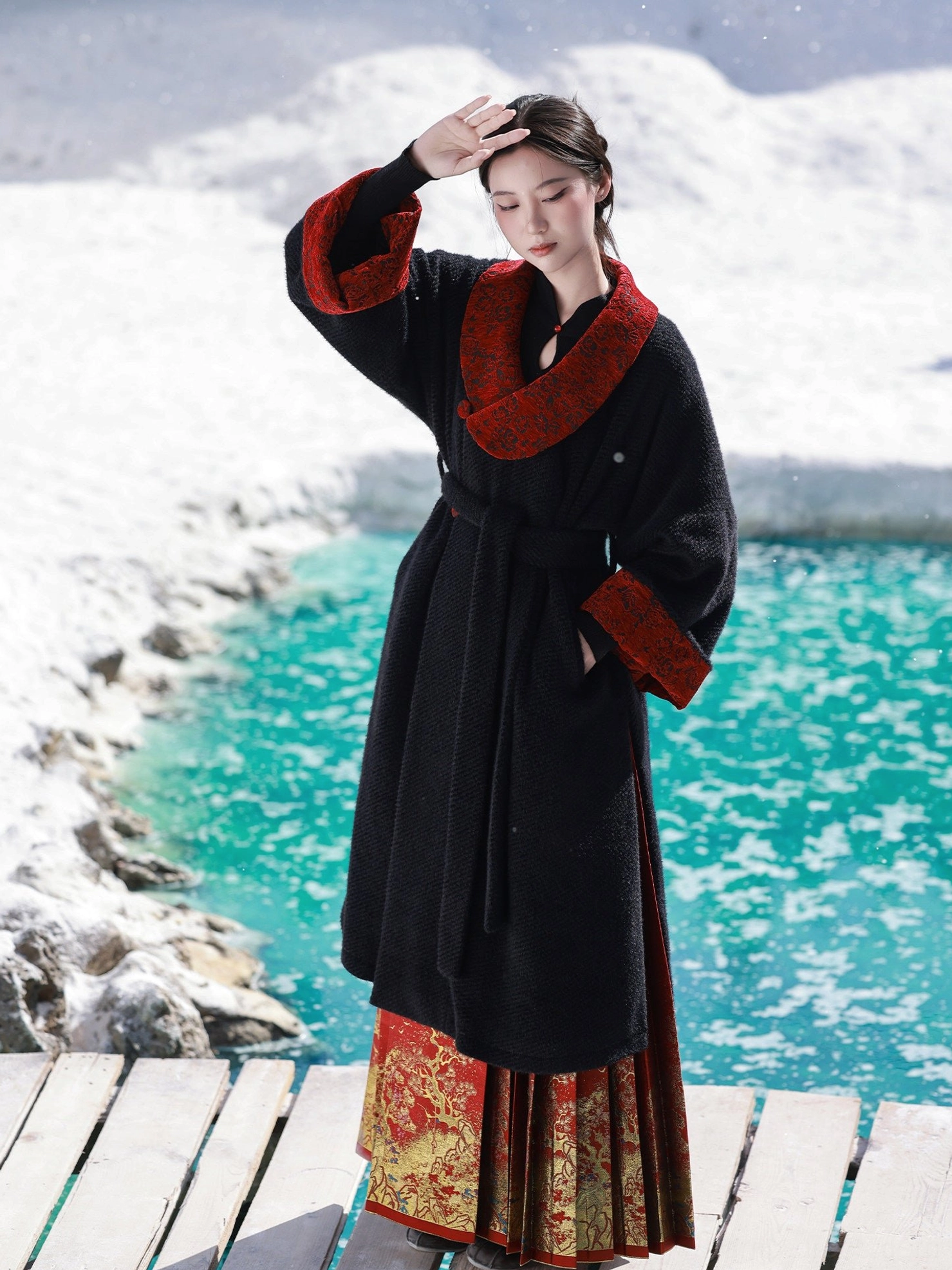 Gryffindor-inspired Tang Dynasty Hanfu winter coat in black chenille with red jacquard collar, styled on a snowy lakeside dock
