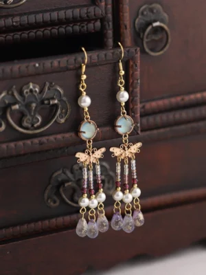 Traditional Chinese butterfly tassel earrings with white faux pearls, lake-blue stone pendants, gold ear hooks, bronze butterfly charms, layered bead tassels, and purple teardrop drops