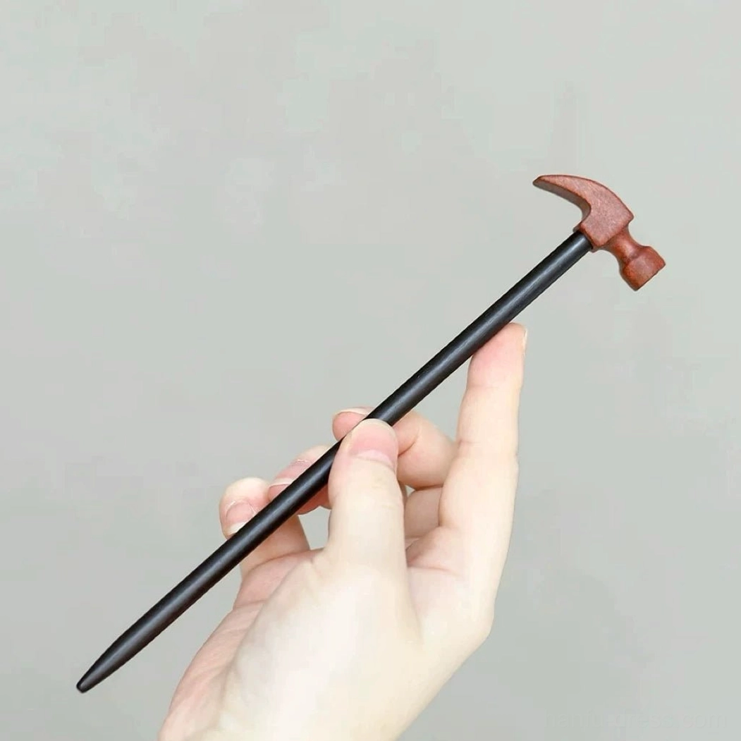Hand holding a smooth two-tone hammer-shaped Chinese hair stick to show its size and polished finish
