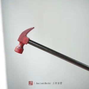 Side view of reddish-brown claw hammer Chinese hair stick with a smooth dark shaft on a light gray studio background