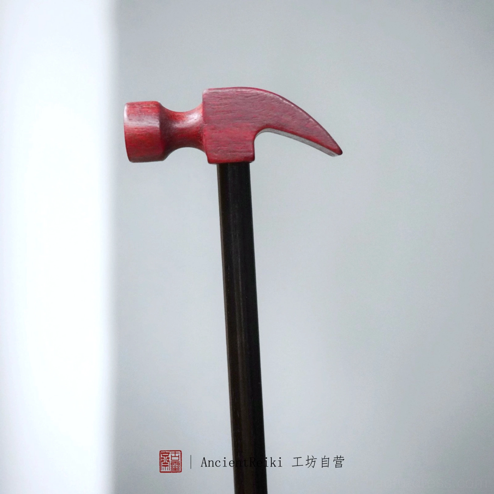 Front close-up of novelty claw hammer Chinese hairpin with compact reddish-brown top and long dark handle