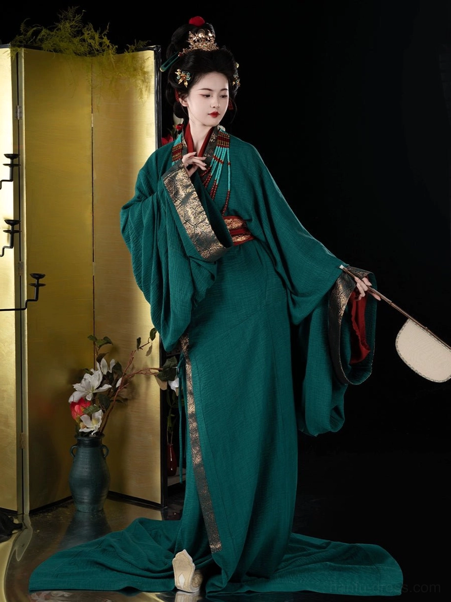 Elegant side pose wearing an emerald green Han Dynasty straight hem Hanfu robe with gold decorative trim, red waist belt, and silk fan