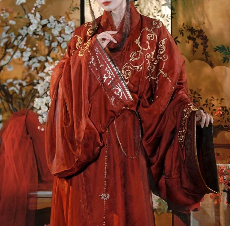 Close-up front view of reddish-brown Hanfu fabric featuring traditional cross-collar construction, delicate gold cloud embroidery, layered waist belt, and hanging decorative chains