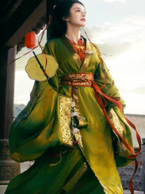 Traditional Han Dynasty Hanfu robe in olive green satin with red and gold collar details, decorative waist trim, hanging lantern hair accessory, and round gold fan