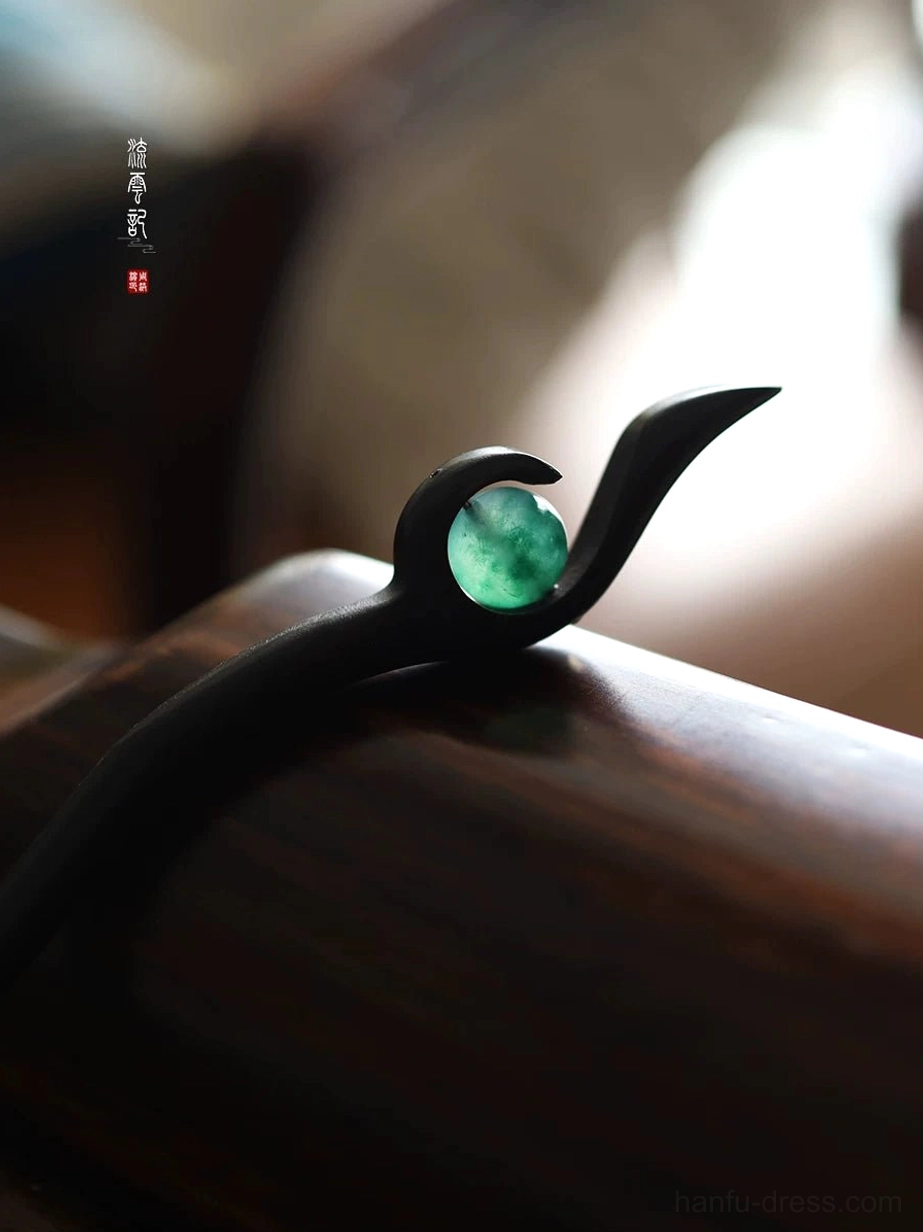 Close-up of handcrafted Chinese hair stick showing natural black wood grain, slim polished shaft, and round green jade hair ornament