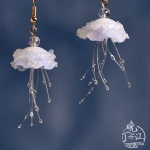 Front view of handcrafted jellyfish Chinese earrings with layered translucent pendants clear spacer beads and elegant gold ear hooks on a dark blue background
