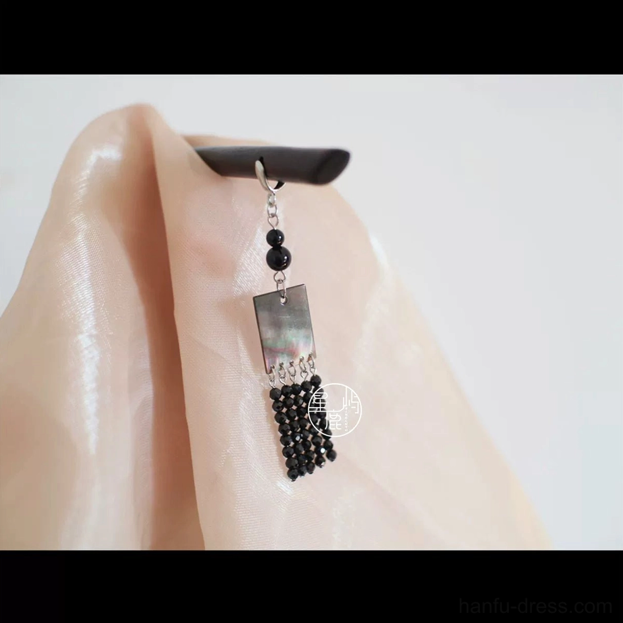 Close-up of handmade Chinese hair stick with dark wood head, silver-tone chain, black round beads, square metal charm, and dense beaded tassel