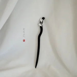 Handmade Chinese hair stick shown from an angled view with polished dark wood and delicate silver floral orchid ornament