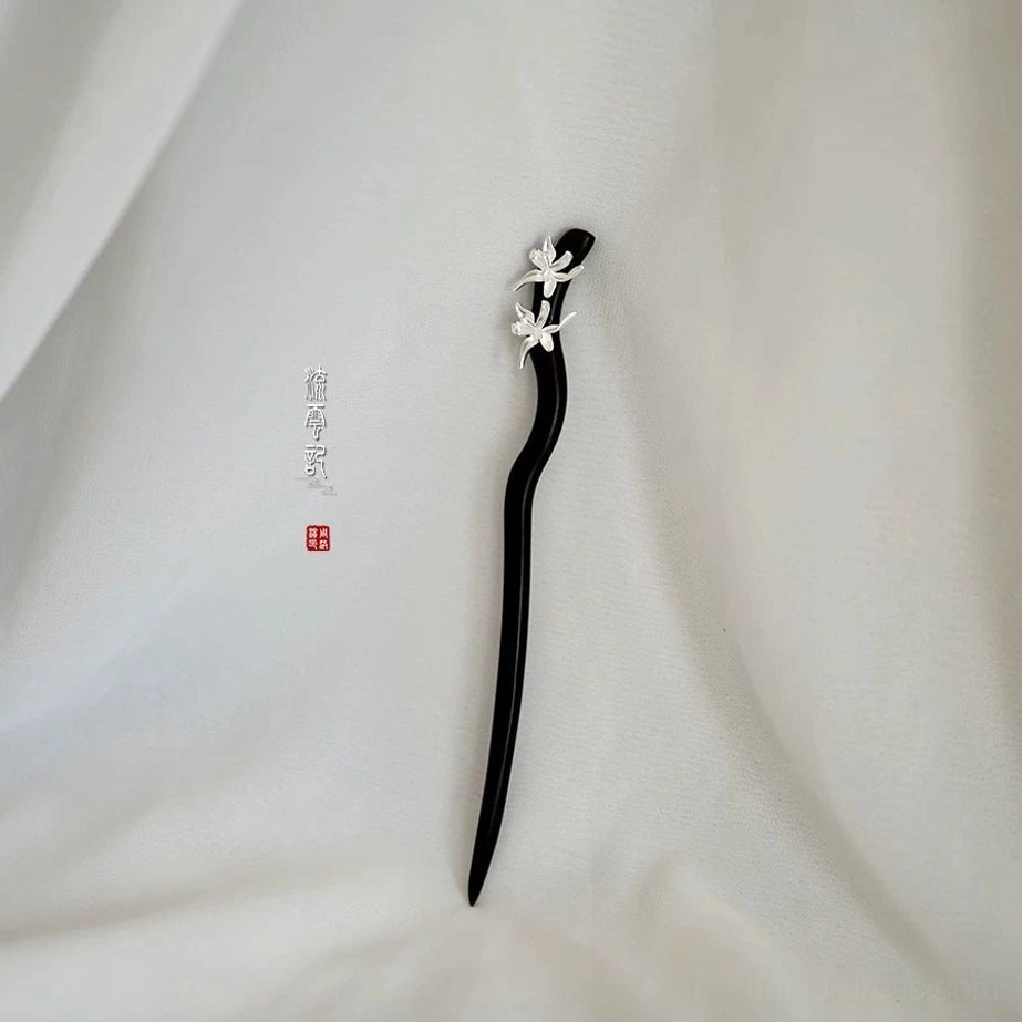 Handmade Chinese hair stick shown from an angled view with polished dark wood and delicate silver floral orchid ornament