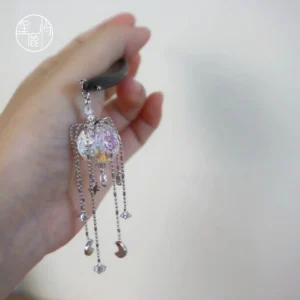 Handheld view of a handmade Chinese hair stick with sparkling crystal ball pendant silver tassel chains and star moon charms