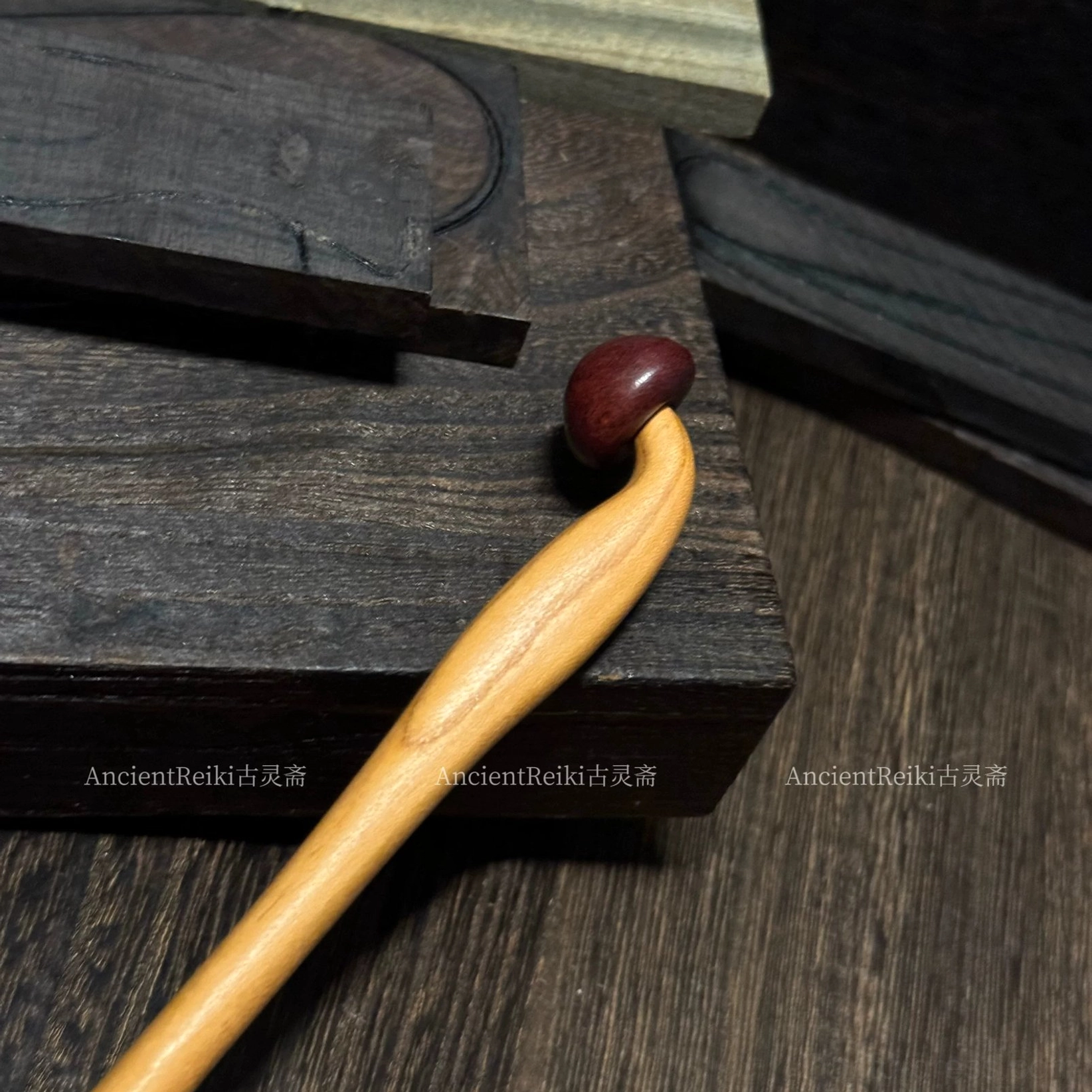 Side top view of a handmade mushroom hair stick with a slim pointed wooden tip, rounded reddish-brown finial, and natural wood grain