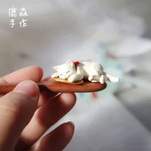 Handheld close-up of a wooden Hanfu hair stick featuring a lifelike sleeping white cat with a red collar bow and traditional Chinese hair accessory styling