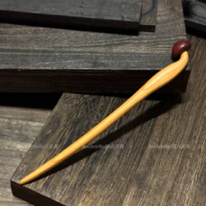Handmade wooden mushroom Chinese hair stick with a light polished wood shaft and dark reddish-brown mushroom-shaped top displayed on a dark wooden table