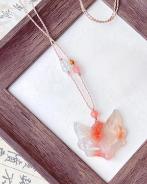 Handwoven Chinese necklace with a carved natural agate fox pendant, rose-gold braided cord, pink white and orange beads, and vintage Chinese calligraphy background