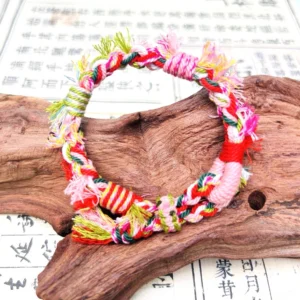 Handwoven Tibetan-inspired Chinese bracelet with colorful braided cords and multicolor tassel displayed on a wooden decorative piece with ancient Chinese calligraphy