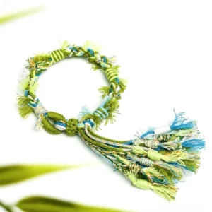 Handwoven Tibetan-inspired knot tassel Chinese bracelet in green blue and cream braided cords shown in a flat lay with leafy accents