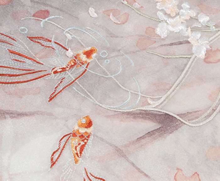 Close-up of traditional Chinese hanfu embroidery showing orange-red carp, silver water ripples, pink flowers, and white blossoms on sheer gradient fabric