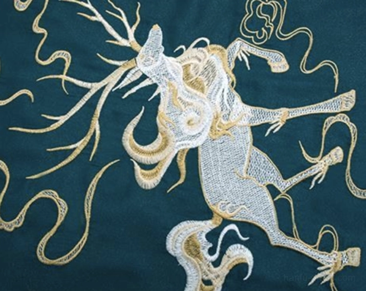 Detailed hanfu embroidery featuring a silver and gold mythical deer with long antlers surrounded by golden cloud patterns