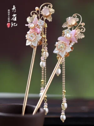 Overhead view of decorative Hanfu hair sticks with pink resin flowers gold metalwork and dangling pearl tassels