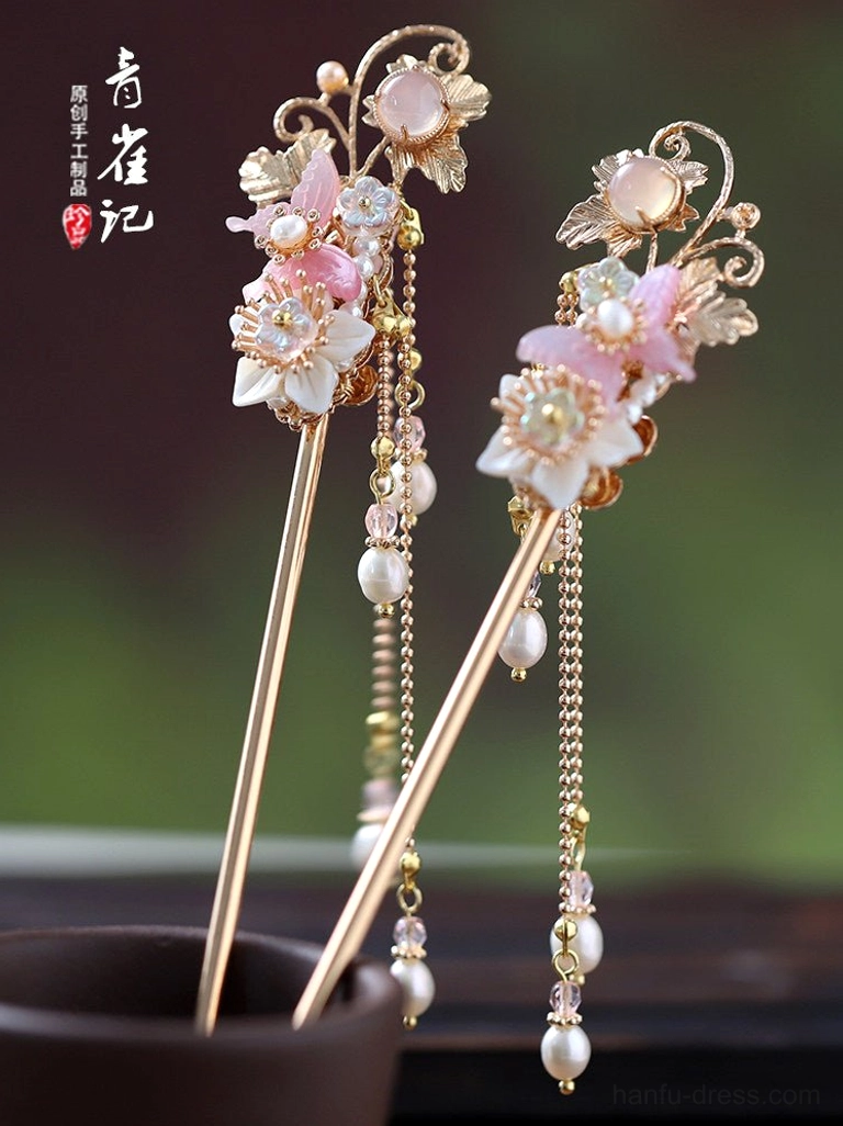 Overhead view of decorative Hanfu hair sticks with pink resin flowers gold metalwork and dangling pearl tassels