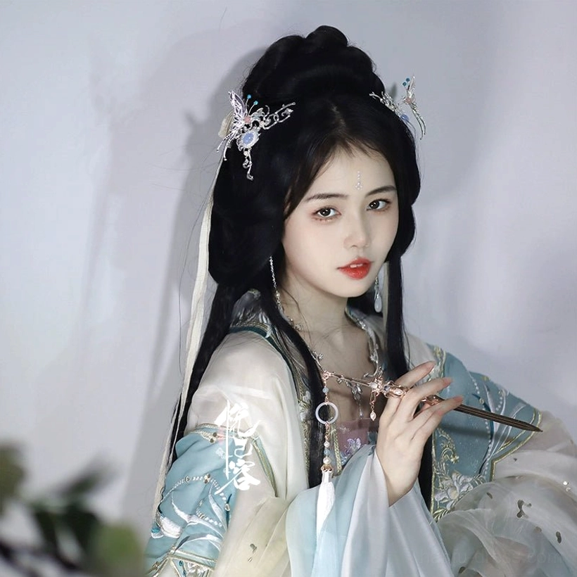 Model wearing a light cyan white hanfu outfit with a traditional coiled hairstyle decorated with a crescent butterfly Chinese hair pin