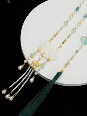 Chinese style Hanfu tassel necklace displayed on a white tray, featuring a white longevity lock pendant, gold floral ornament, teardrop pearl-like drops, and dark green tassel