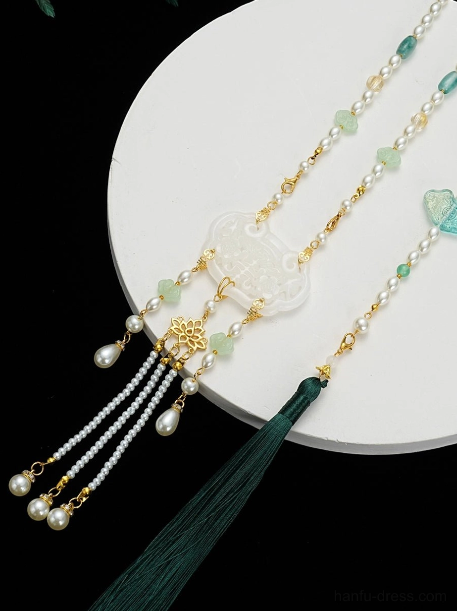 Chinese style Hanfu tassel necklace displayed on a white tray, featuring a white longevity lock pendant, gold floral ornament, teardrop pearl-like drops, and dark green tassel