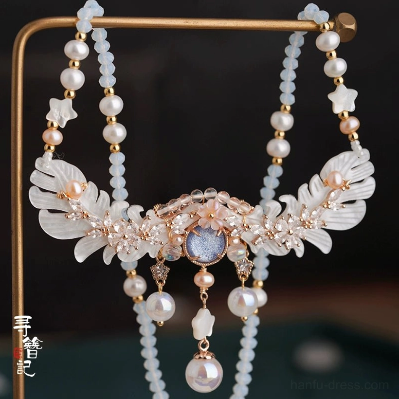 Traditional Hanfu yingluo necklace with long double-sided beaded tassels, star charms, layered pearl pendants, and a blue-gray gemstone centerpiece on a vintage display stand
