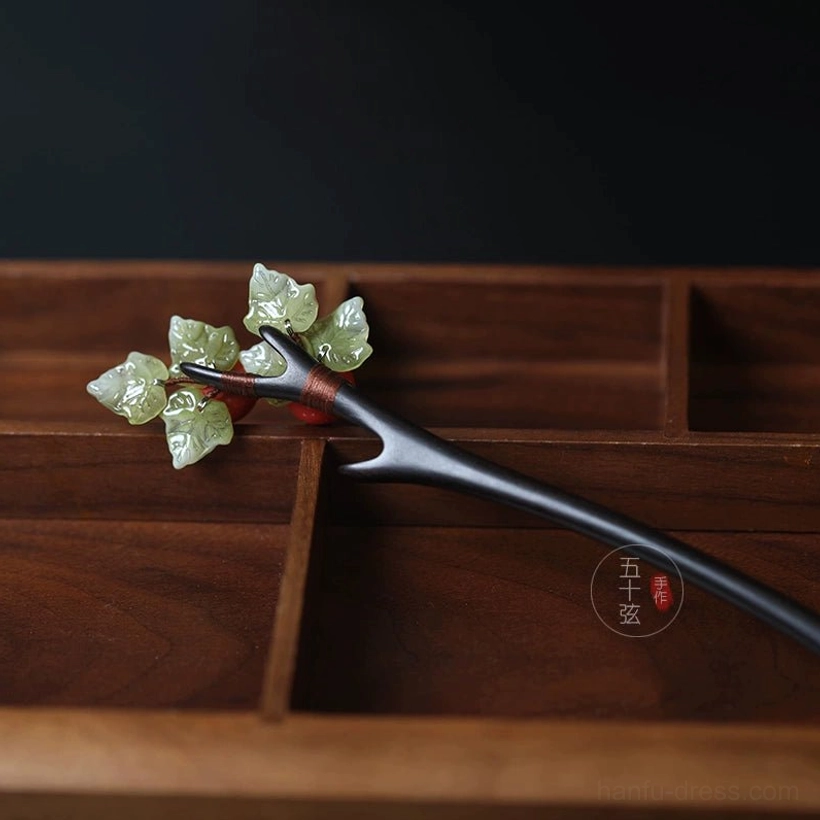 Hawthorn Hanfu hair accessory with red fruit and green leaf decoration arranged on a dark wooden hair stick
