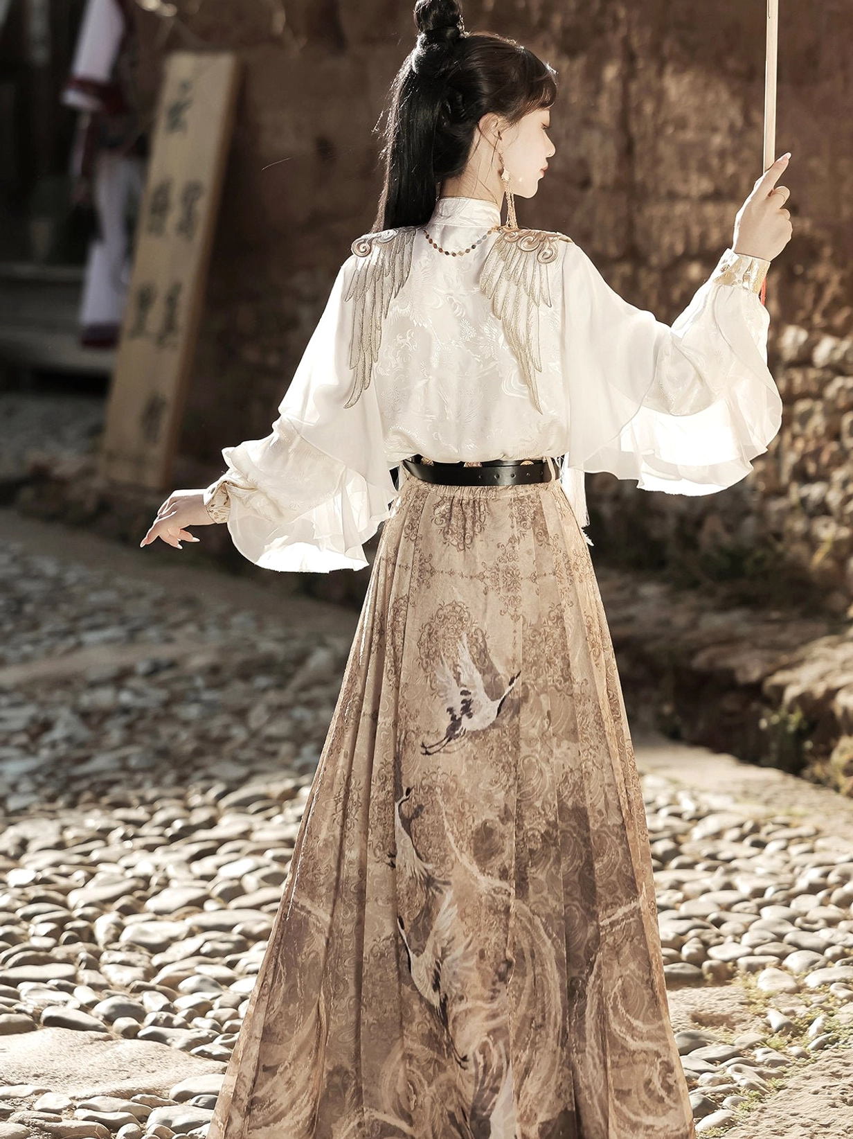 Back view of Heavenly Envoy Hanfu outfit showing the white long sleeve top, exposed back styling, waist tassel, black belt, and printed khaki horse face skirt