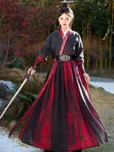 Front view of red and black Hongchen warrior Hanfu set featuring embroidered cross collar, fitted top, gradient pleated skirt, metal style waist buckle, and sword in bamboo garden