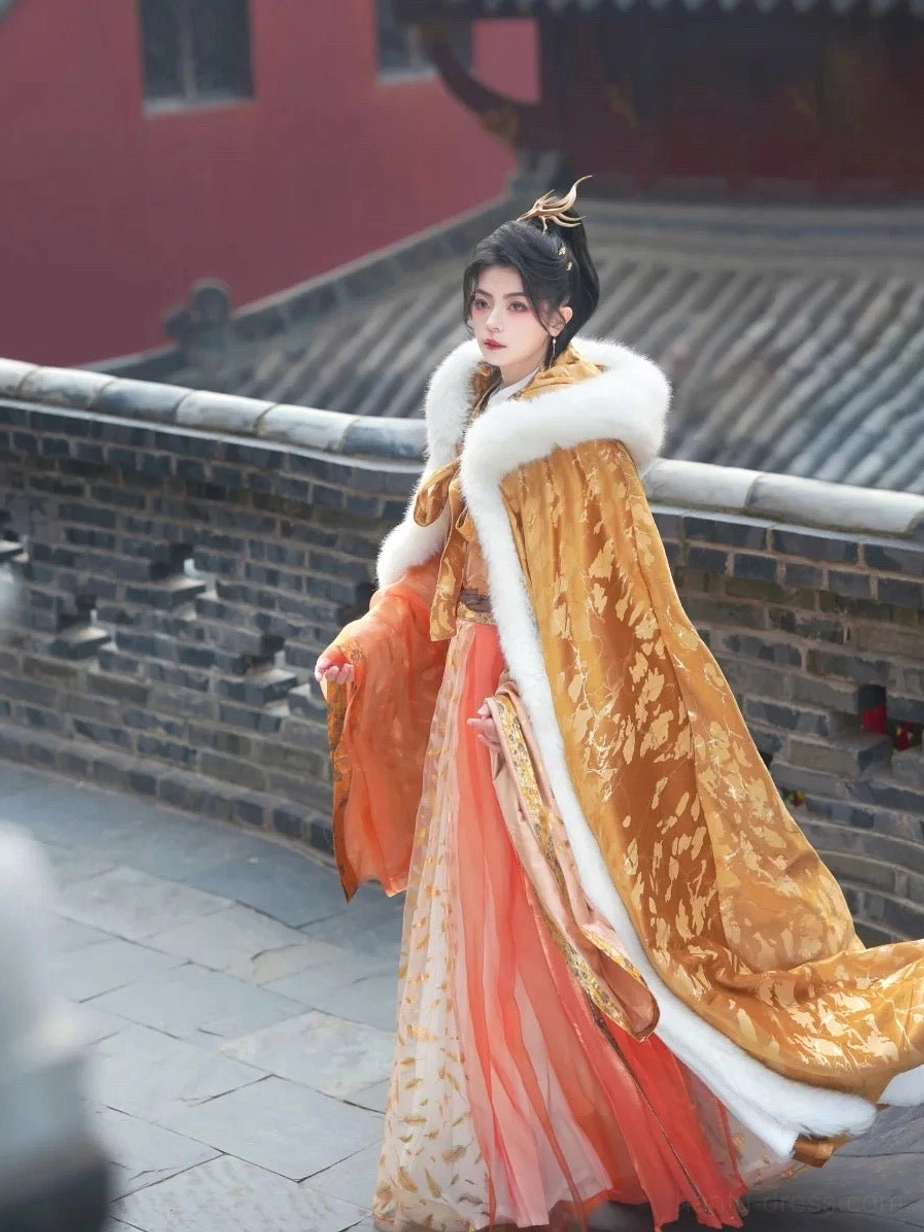 Side profile of a hooded gold embossed velvet Hanfu cloak with a sweeping train and white faux fur trim on an ancient Chinese city wall