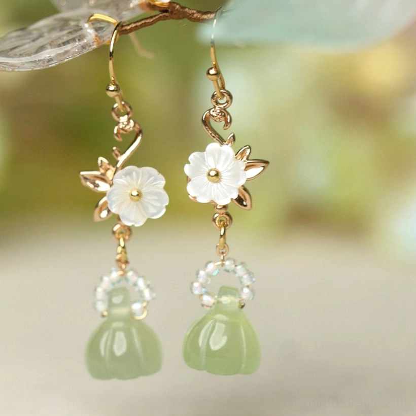 Close-up hook lotus pod earrings featuring gold ear hooks paired white floral charms clear bead rings and green pendants