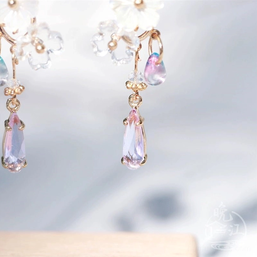 Macro detail of Hua Luo Chinese earrings showing rose gold tone links, white shell flower charms, crystal beads, and purple pendants