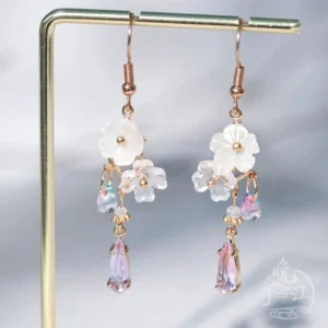 Close frontal view of Hua Luo Hanfu floral dangle earrings with white flower charms, crystal clusters, and purple gradient drops