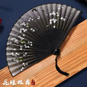 Huadie plum blossom butterfly Chinese folding hand fan with dark black surface, hollow bamboo ribs and black tassel displayed on a dark blue background