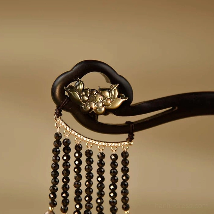 Side close-up of traditional Chinese ebony tassel hair stick with silver floral lotus detail and straight black bead strands