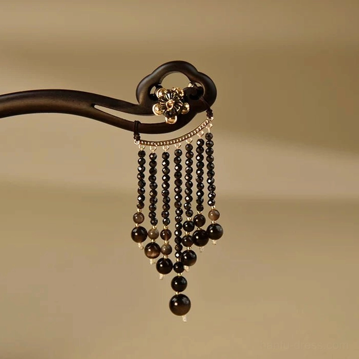 Close-up of cloud-shaped ebony Chinese hair stick with silver lotus ornament and graduated black bead tassel