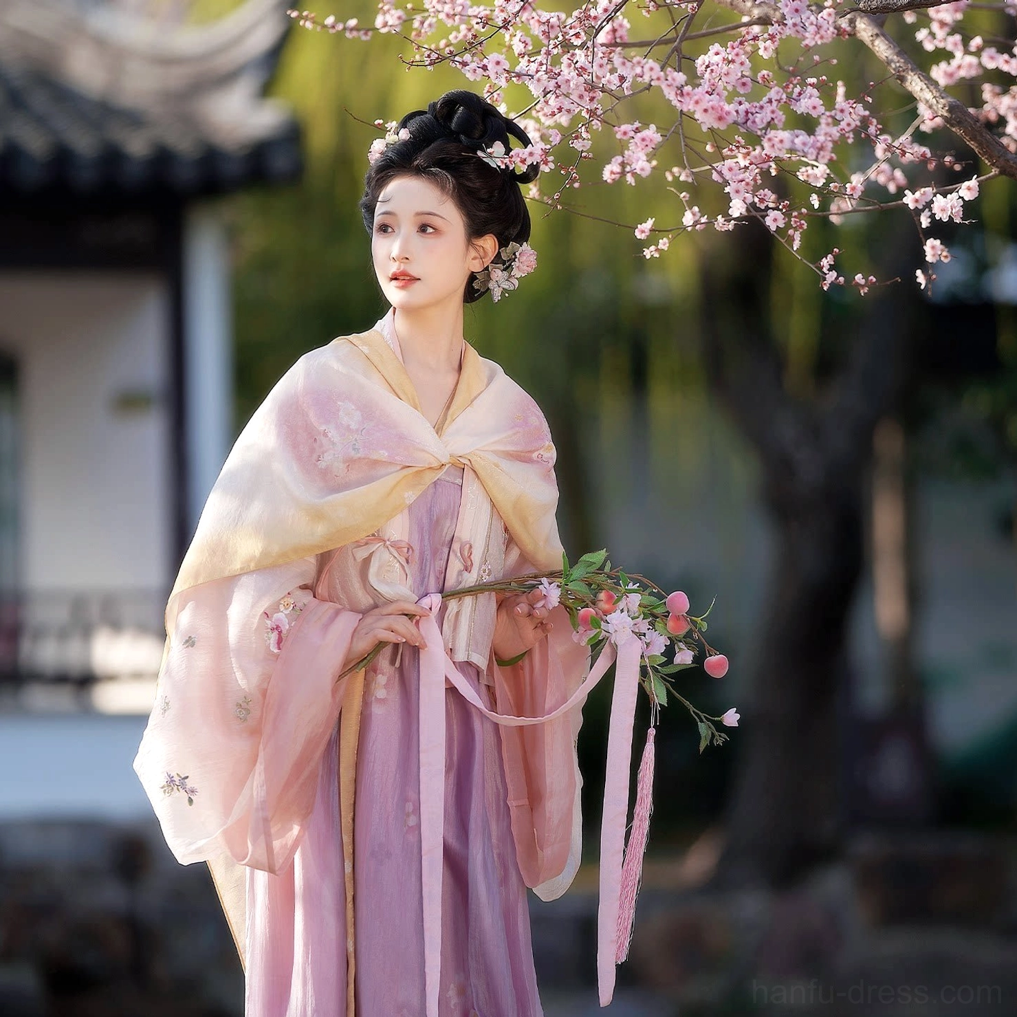 Side portrait of a model wearing the Hundred Flowers Scroll Tang Dynasty hanfu set with tied waist sash, gradient shawl and lavender floor-length qixiong skirt in a willow garden