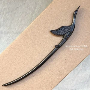 Matte dark immortal crane Hanfu hair stick with realistic carved bird and wing details shown against a neutral gray background
