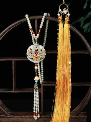 Imperial Chinese yingluo necklace displayed on a wooden shelf with layered pearl bead chains, white floral pendant and long golden silk tassels