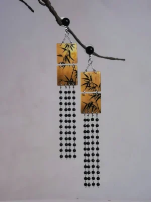Angled view of tan square bamboo leaf tassel earrings for Hanfu with black bead tassels and silver tone chains