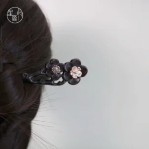 Ink plum blossom Chinese hair stick worn in a braided Hanfu updo, featuring a dark wooden pin with pink floral ornaments and gemstone accents