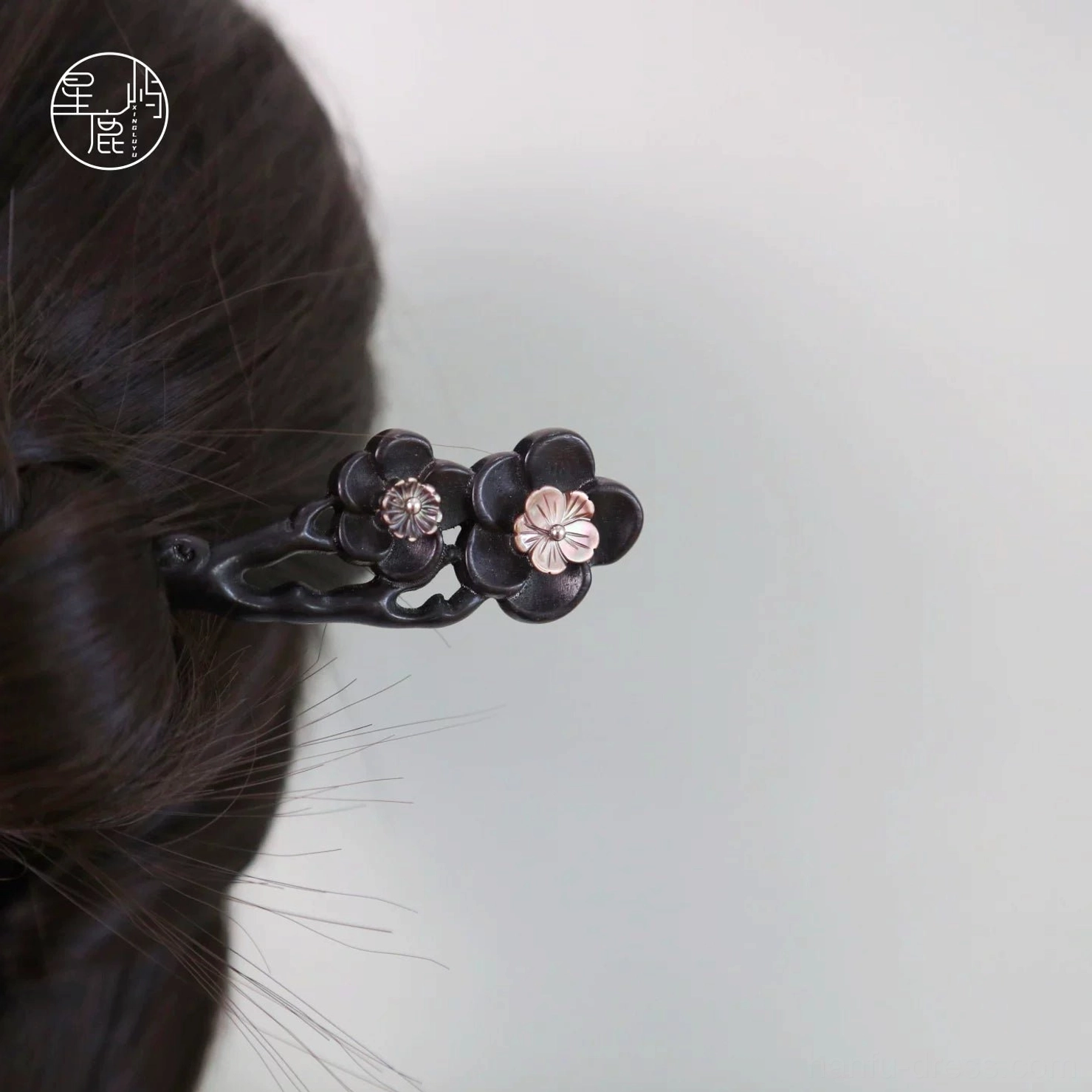 Ink plum blossom Chinese hair stick worn in a braided Hanfu updo, featuring a dark wooden pin with pink floral ornaments and gemstone accents