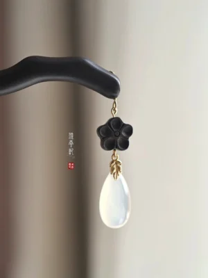 Ink plum blossom Chinese hair stick close-up with dark curved wooden pin, black flower charm, gold-tone links and white teardrop pendant