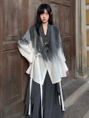 Front three quarter view of a woman wearing an oversized ink wash tie dye modern Hanfu cardigan with grey to off white gradient print, wrap V neck, long sleeves, and adjustable side sashes